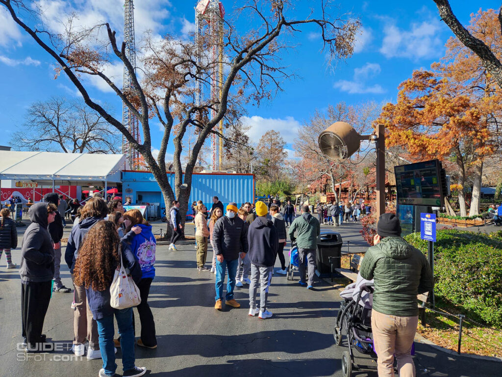 Crowd of guests gathered around a wait time screen looking for open rides