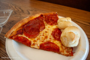 A slice of New York-style pizza made with fresh dough and garlic knots from Primo's